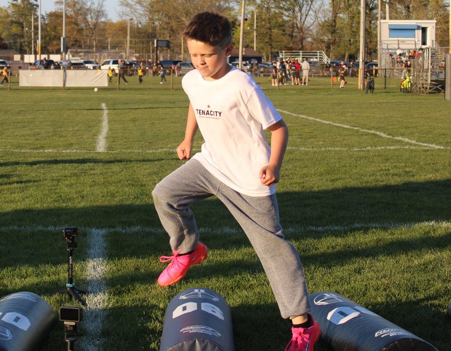 Young athlete in a Tenacity shirt jumping training bags