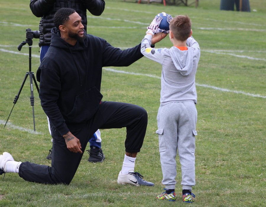 Tenacity coach kneeling to congratulate a young football player on the field