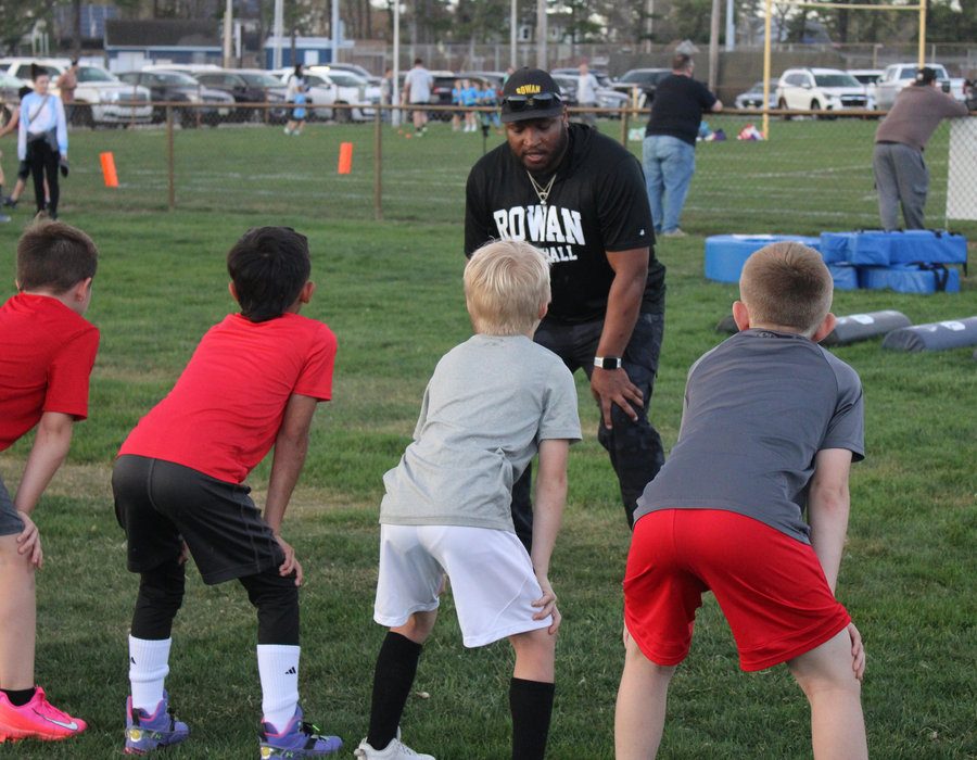 Coach instructing a group of young athletes in ready position